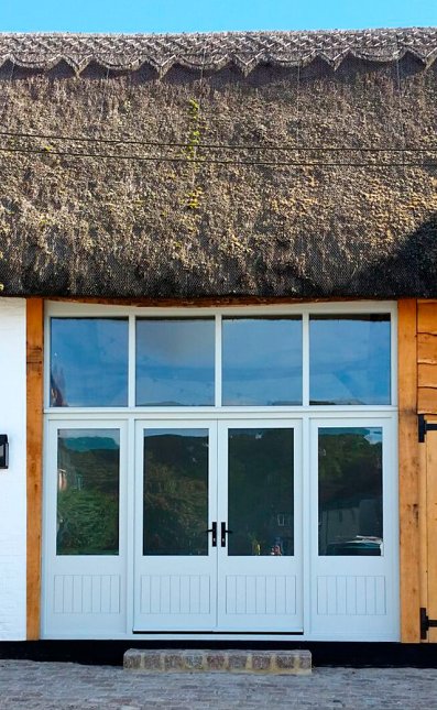 Pair of hardwood doors with side lights to match. Glaze window above. Pairs of oak garage doors to each side.