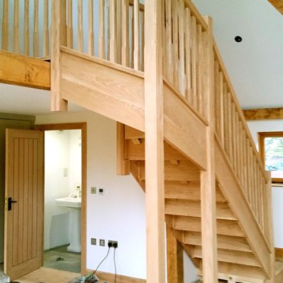 Oak staircase in a barn going up to an open balcony