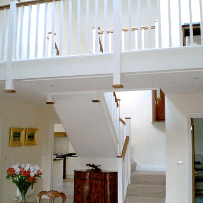 Painted staircase with hardwood handrail and matching balcony